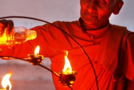 A monk lighting votive candles, Kataragama, Sri Lanka